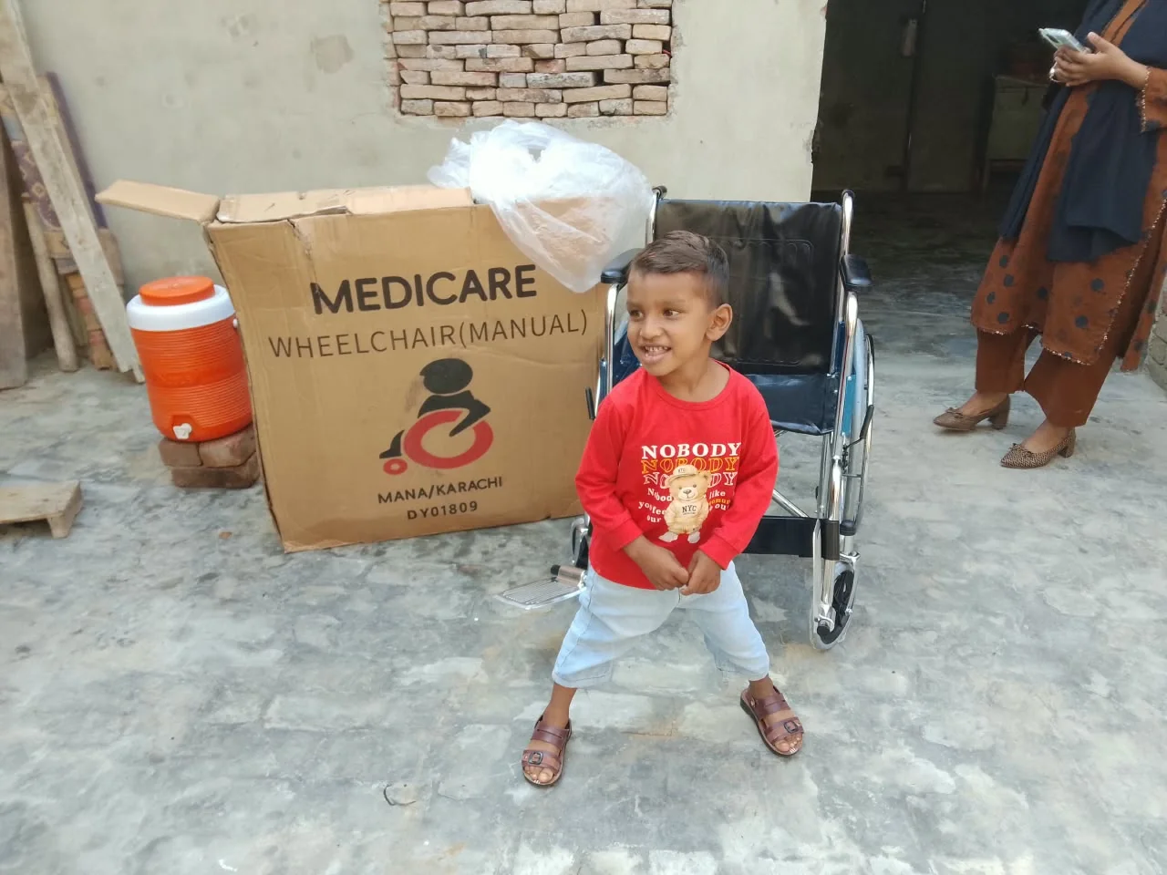 A young community member beside a wheelchair during a visit