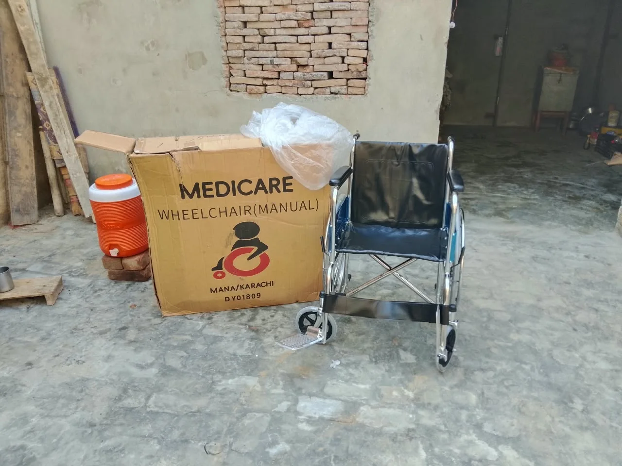 A wheelchair beside its delivery carton at the home