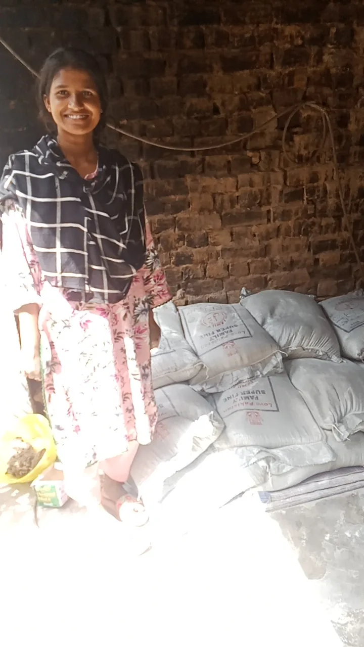 A woman standing beside sacks of supplies